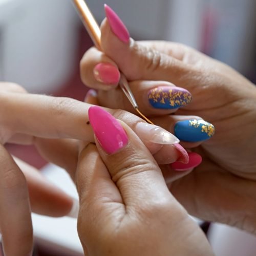 closeup of manicurist doing nail art to a client